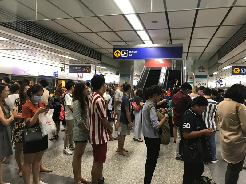 A typical scene from Bangkok's subway system during peak rush hour when commuters are leaving work and heading home, showing the crowded queues that form during this busy time of day.